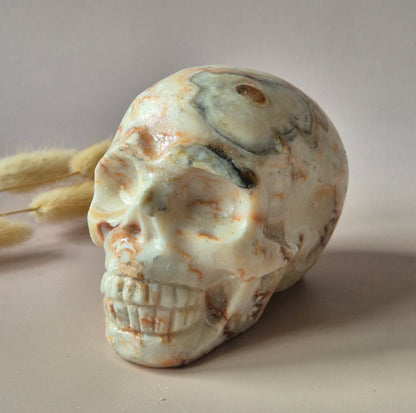 Grote handgeslepen Crazy Lace Agaat skull van circa 700 gram met natuurlijke crème en caramelkleurige patronen en glanzende afwerking.