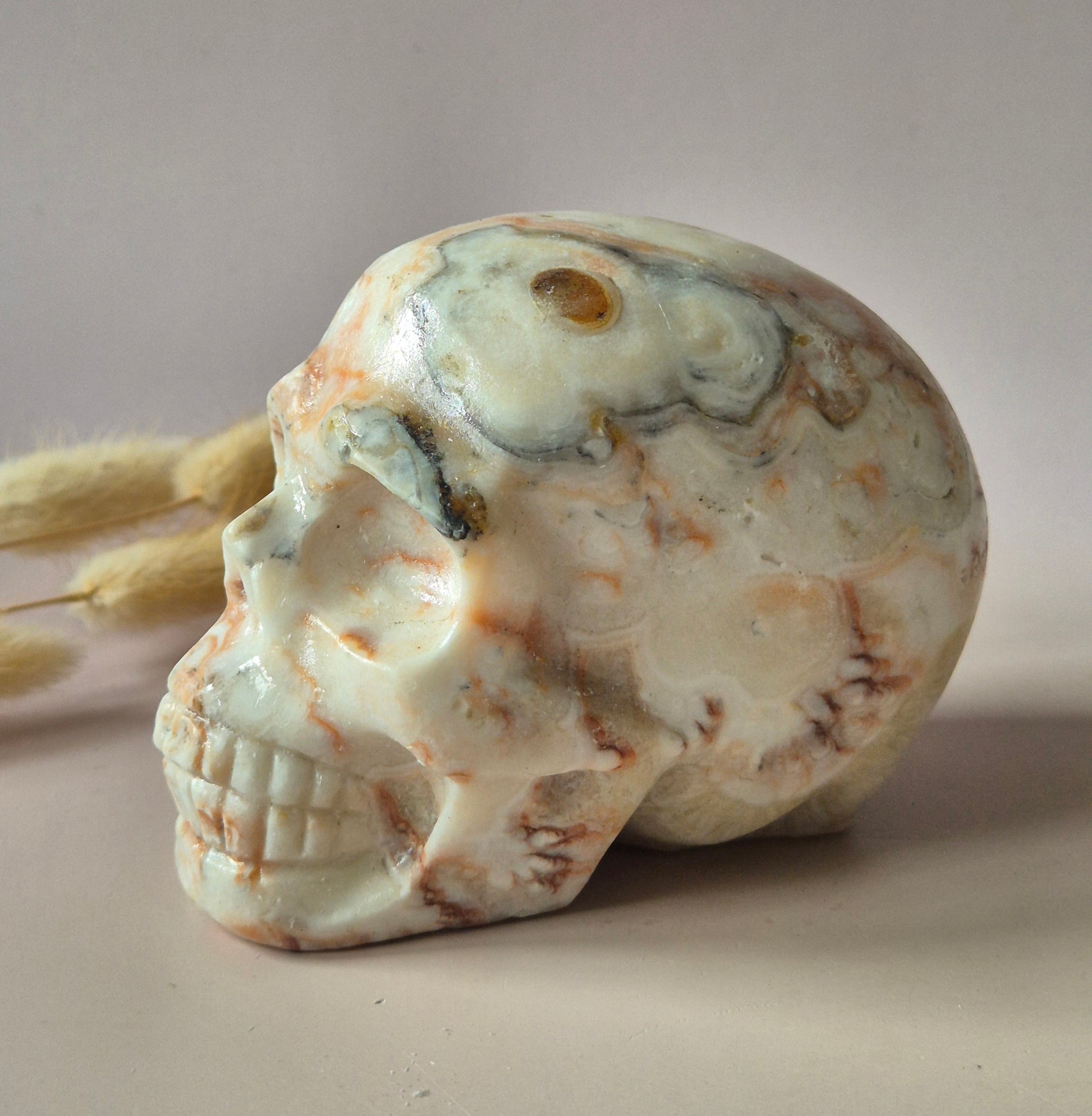Grote handgeslepen Crazy Lace Agaat skull van circa 700 gram met natuurlijke crème en caramelkleurige patronen en glanzende afwerking.